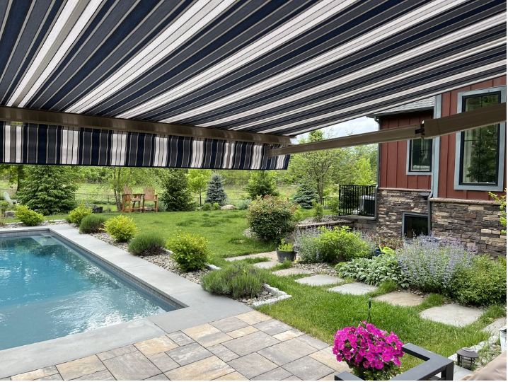 Retractable awning over a patio surrounded by landscaping.